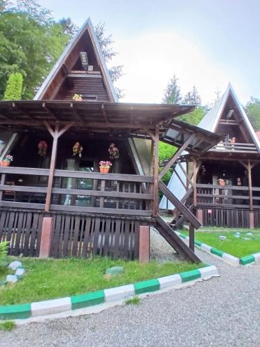 a cabin with a thatched roof and a fence at Chalet A Frame Sinaia in Sinaia