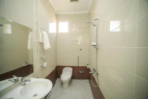 a bathroom with a toilet and a sink and a shower at توارن للشقق المخدومة - اقتصادي in Hail