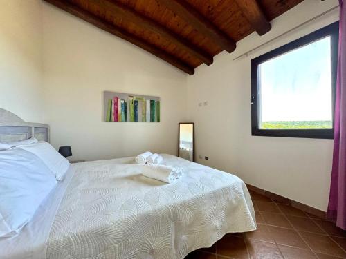 a bedroom with a white bed with a window at Bellevue Bari Sardo in Bari Sardo