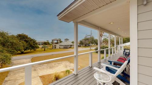 uma varanda com duas cadeiras azuis e vista para uma rua em CLUBHOUSE COTTAGE home em Jekyll Island
