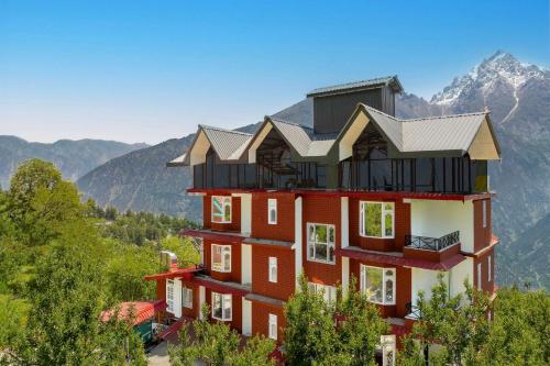a building in the mountains with mountains in the background at Echor - The Alpine Crest in Kalpa