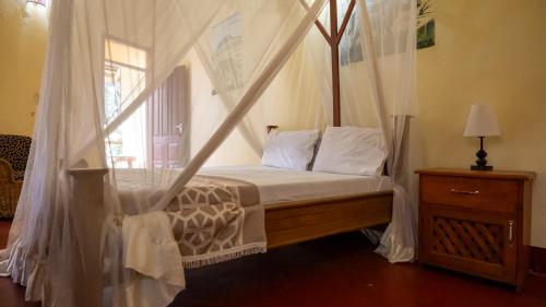 a bedroom with a canopy bed with a window at Vijiji Center Lodge and Safari in Arusha
