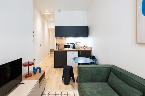 un salon avec un canapé vert et une cuisine dans l'établissement Opéra 4, à Lyon