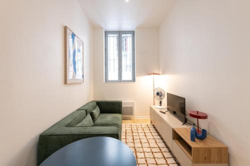 - un salon avec un canapé vert et une télévision dans l'établissement Opéra 4, à Lyon