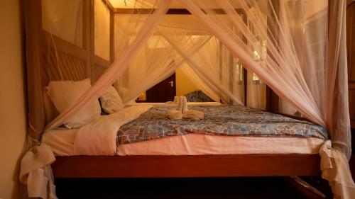 a bedroom with a canopy bed with teddy bears on it at Vijiji Center Lodge and Safari in Arusha