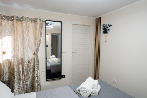 una camera da letto con specchio e un letto con asciugamani di Meravigghia Syracusae Home a Siracusa