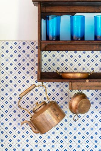 a shelf with blue glasses and a pot on a wall at Nel borgo i gatti di Monet in Castelnuovo di Porto