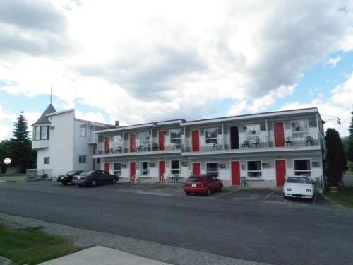 a large white building with cars parked in a parking lot at Almo Court Motel in Cranbrook