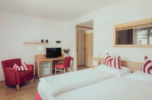 a hotel room with two beds and a television at Romantik Spa Hotel Elixhauser Wirt in Elixhausen