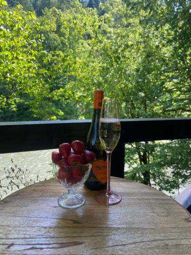 a table with a bottle of wine and a bowl of apples at Hotel Tys in Dilove