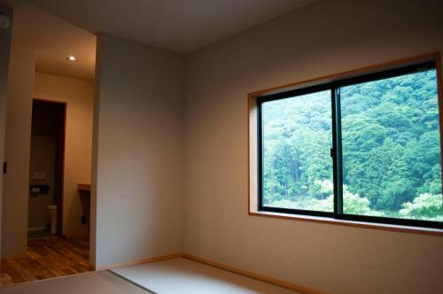 an empty room with a large window with a forest at SEN.RETREAT TAKIJIRI in Tanabe