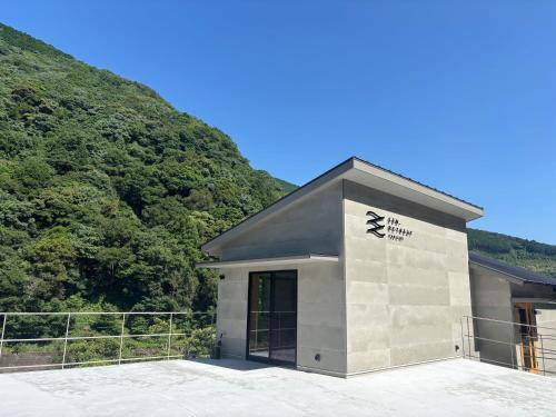 a building in front of a hill with trees at SEN.RETREAT TAKIJIRI in Tanabe