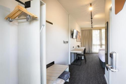 a small room with a bed and a desk at Nightcap at Sandown Park Hotel in Noble Park