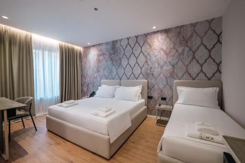 a hotel room with two beds and a table at Ermes Luxury Hotel in Durrës