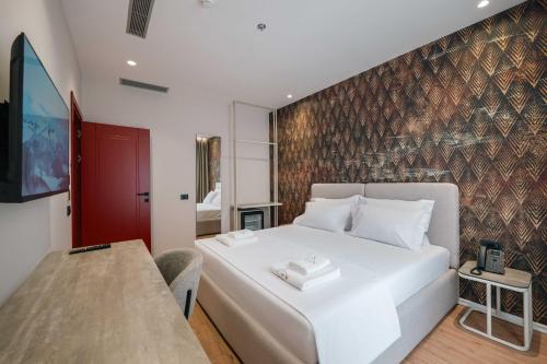 a bedroom with a white bed and a red wall at Ermes Luxury Hotel in Durrës