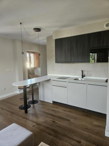 a kitchen with white cabinets and a table in it at La Barata Apartamentos in Colombres
