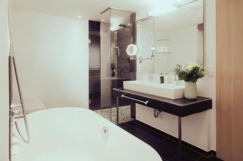 a white bathroom with a sink and a mirror at Romantik Spa Hotel Elixhauser Wirt in Elixhausen