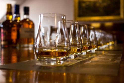a row of glasses of whiskey sitting on a table at Kimpton Charlotte Square by IHG in Edinburgh
