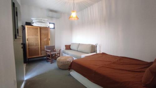 a bedroom with a bed and a couch and a chair at Salty Yard Holiday Home in Serifos Chora