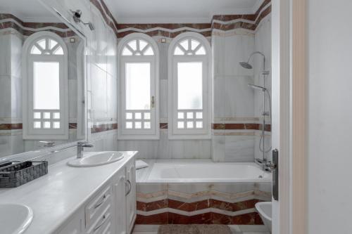 a white bathroom with two sinks and a tub at Palacio Suites Marbella in Marbella