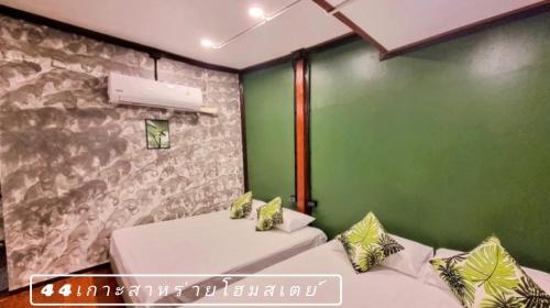 a room with two beds and a green wall at 44Kohsaraihomestay 44เกาะสาหร่ายโฮมสเตย์ in Satun