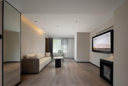 a living room with a couch and a tv on a wall at Atour Hotel Hangzhou Hubin Pinghai Road in Hangzhou