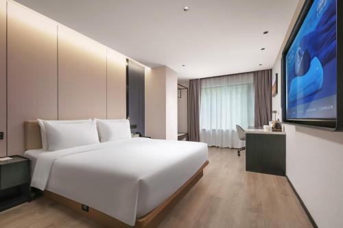 a bedroom with a large white bed and a flat screen tv at Atour Hotel Hangzhou Hubin Pinghai Road in Hangzhou