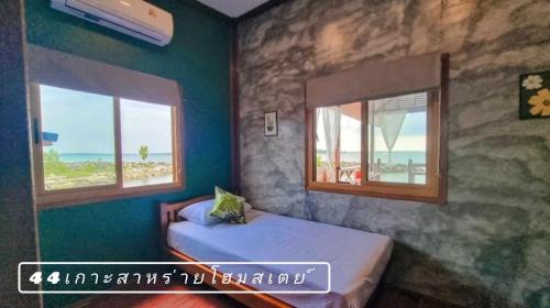 a bedroom with a bed and two windows with the ocean at 44Kohsaraihomestay 44เกาะสาหร่ายโฮมสเตย์ in Satun