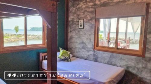 a bedroom with two windows and a bed with a view of the ocean at 44Kohsaraihomestay 44เกาะสาหร่ายโฮมสเตย์ in Satun