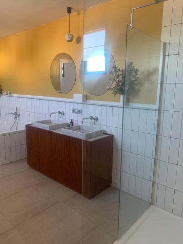 a bathroom with two sinks and a glass shower at De parel van TOMORROWLAND in Niel