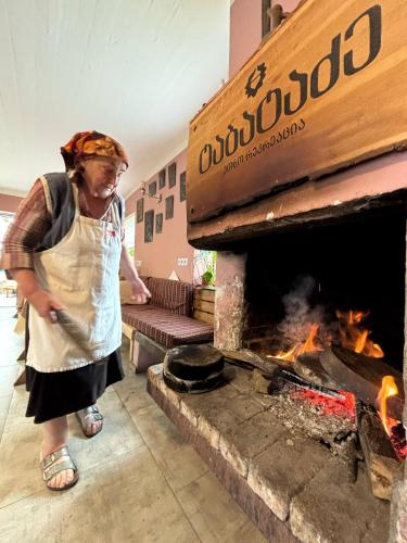 a woman is standing in front of a fireplace at Etno Rekreacia Tabatadze, With in Door & Out door pool 