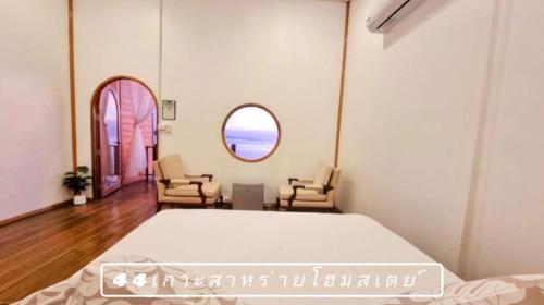 a bedroom with a bed and two chairs and a window at 44Kohsaraihomestay 44เกาะสาหร่ายโฮมสเตย์ in Satun