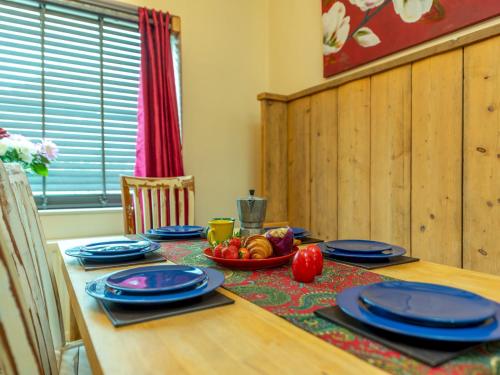 a table with blue plates and a bowl of fruit on it at Pass the Keys Cosy Spacious Garden House in Bridgnorth