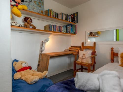 a teddy bear sitting on a blue couch in a bedroom at Pass the Keys Cosy Spacious Garden House in Bridgnorth