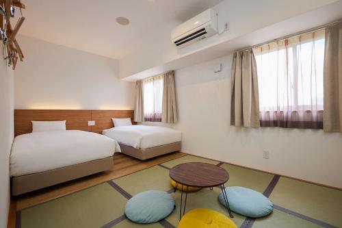 宮古島にあるSmile Hotel Miyakojimaのベッド2台とテーブルと椅子があるホテルの部屋