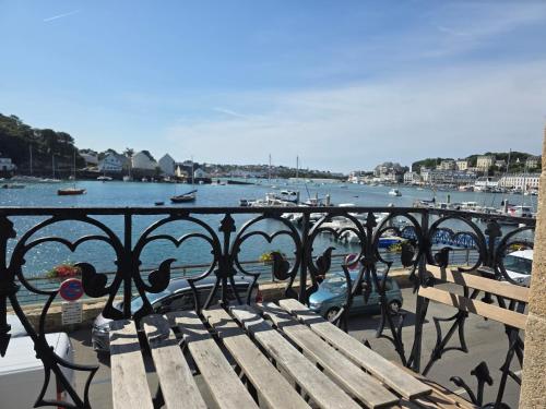 a bench sitting on a balcony overlooking a body of water at Anatoline Audierne Appart'hôtel - Appartements vue Mer - Sea & Harbor Stay in Audierne