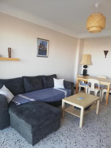 un salon avec un canapé et une table dans l'établissement Appartement PLAGE - LES PIEDS DANS L'EAU, à Canet