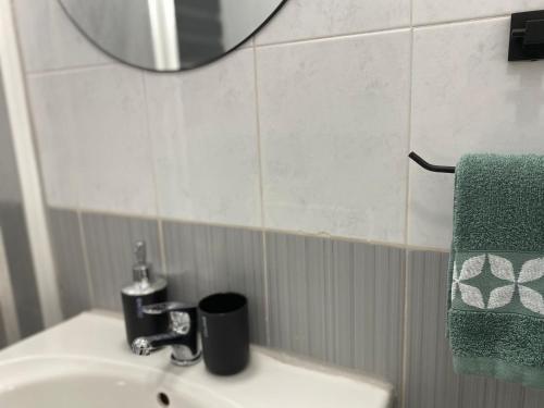 a bathroom sink with a mirror and a green towel at Sea Breeze Retreat - Comfort Apartments in the Heart of Sliema in Sliema