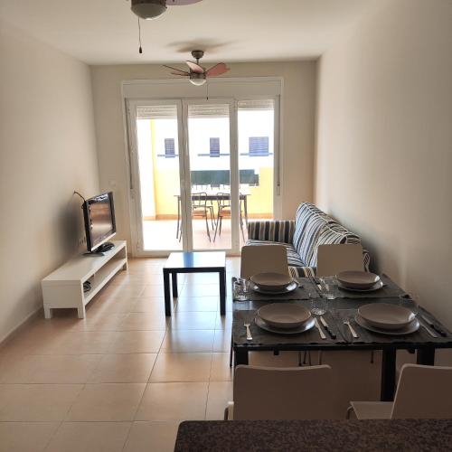 a living room with a table and chairs and a television at Apartamento Luminoso con terraza y parking privado - Vera Playa in Playas de Vera