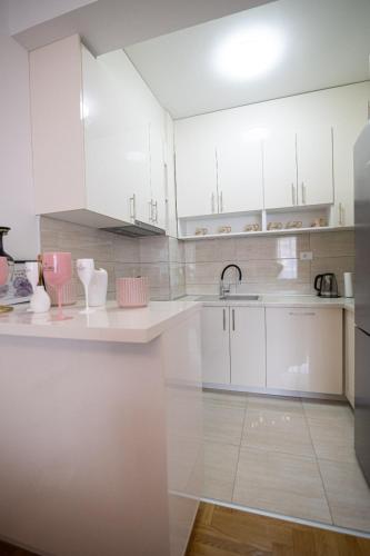 a white kitchen with white cabinets and a sink at Delux in Trebinje