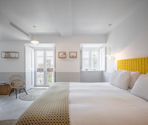 a bedroom with a large white bed with a yellow headboard at toctoctoc lisboa in Lisbon