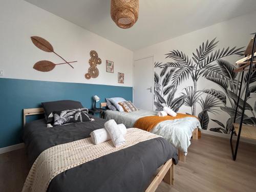 - une chambre avec 2 lits et une fresque murale de palmiers dans l'établissement La Villa des petits bonheurs, à Saint-Quay-Portrieux