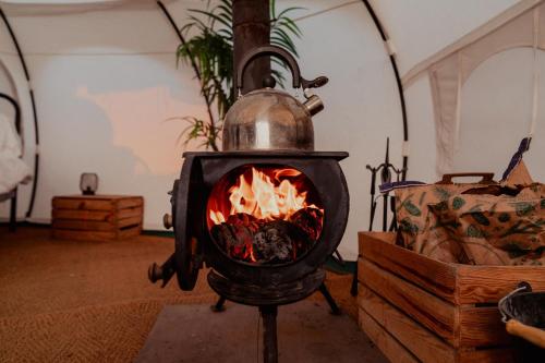 a stove with a tea kettle and a fire at Bamburgh Under Canvas in Bamburgh