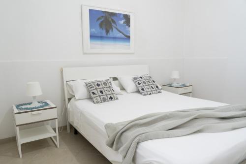 ein weißes Schlafzimmer mit einem weißen Bett und einer Palme in der Unterkunft Stelle Gemelle Residence by ThePuglia in Torre Lapillo