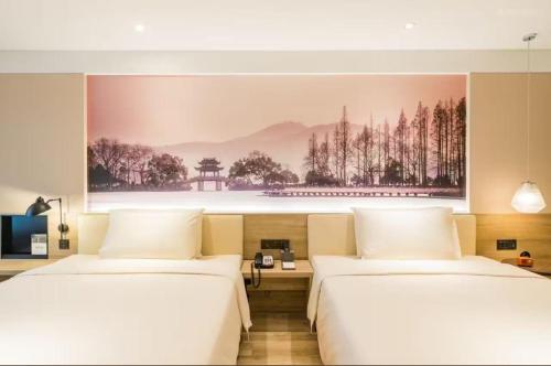 two beds in a room with a painting on the wall at Atour Hotel Hangzhou West Lake Cultural Plaza Shangtang Road in Hangzhou