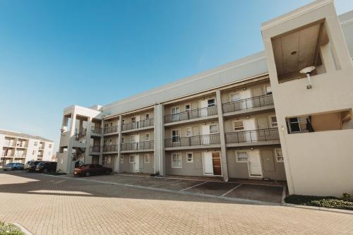 an apartment building with balconies and a parking lot at Muizi Hideaway in Muizenberg