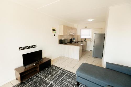 a living room with a blue couch and a kitchen at Muizi Hideaway in Muizenberg
