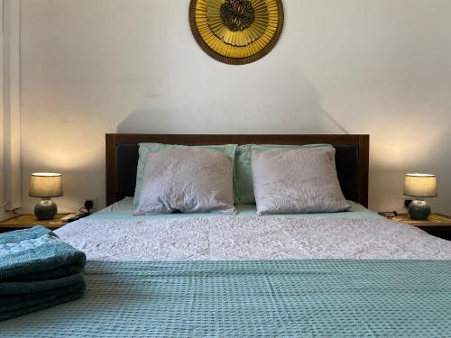 a bed with two pillows and a clock on the wall at Sea Breeze Retreat - Comfort Apartments in the Heart of Sliema in Sliema