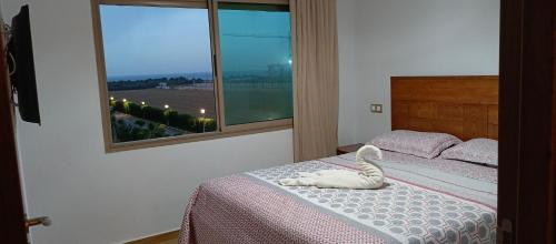 a bedroom with a bed with a white animal on it at Blue Beach only for family in Sidi Rahal