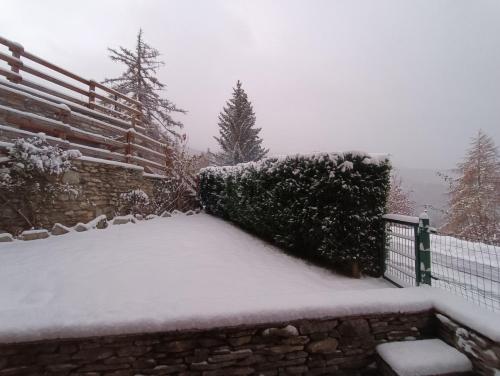 a yard covered in snow with a fence and trees at Casa Richardette Relax in the Woods in Sauze d'Oulx